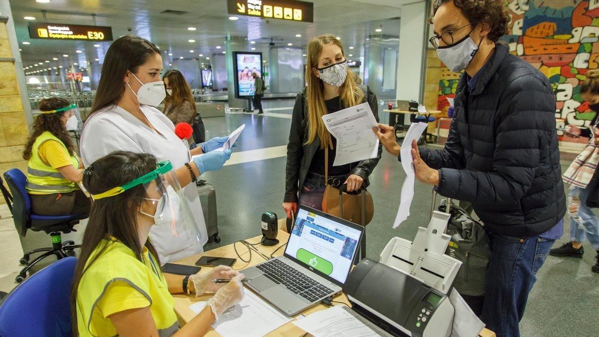 Varios pasajeros muestran su pasaporte Covid.