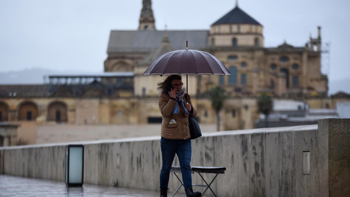 Una mujer cruza por el Puente Romano bajo una ligera lluvia.