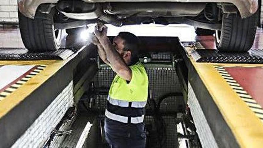 Un mecánico inspecciona un coche en la ITV de Gijón.