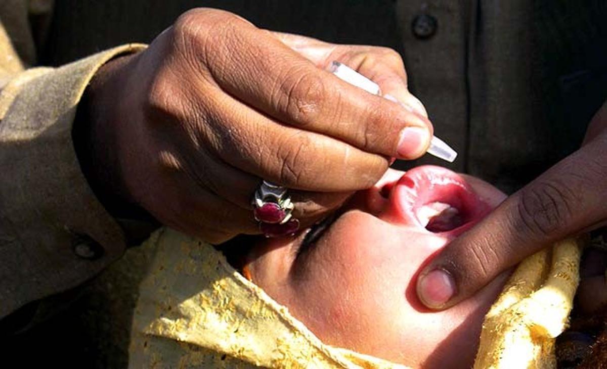 Un trabajador de sanidad da la vacuna de la polio a una niña en Chamán (Pakistán).