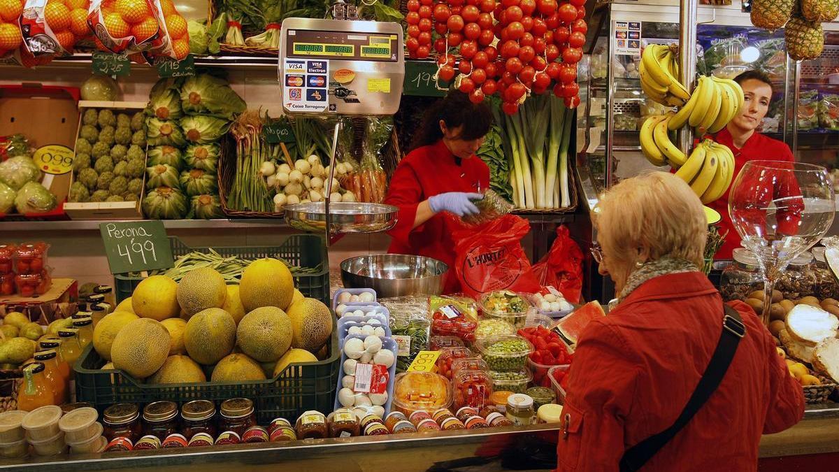 Jubilada compra en un puesto de frutas y verduras de un mercado.