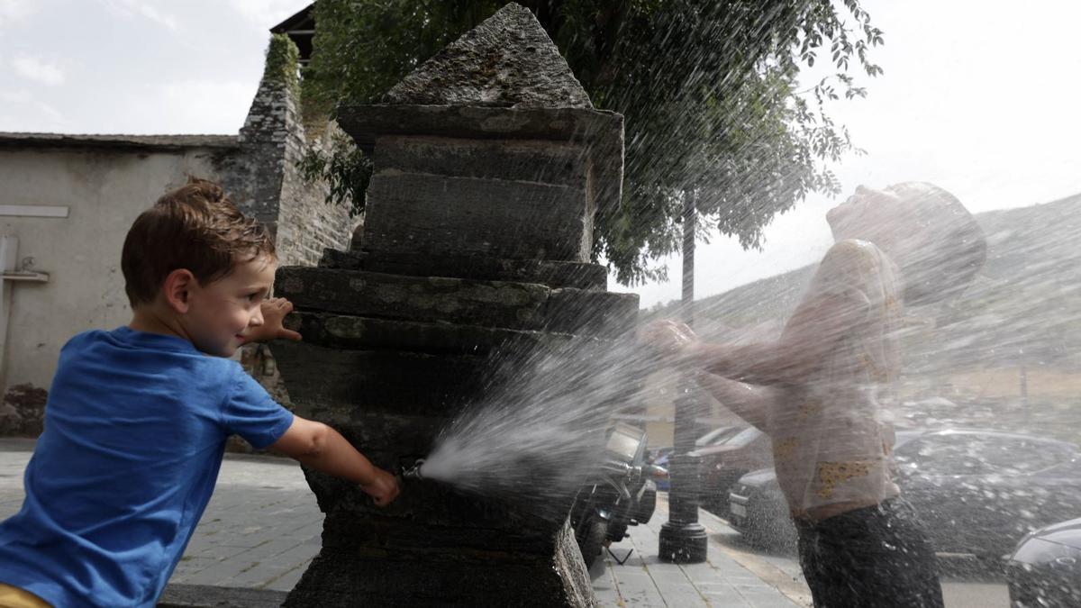 Dos niños se refrescan en una fuente de San Antolín de Ibias