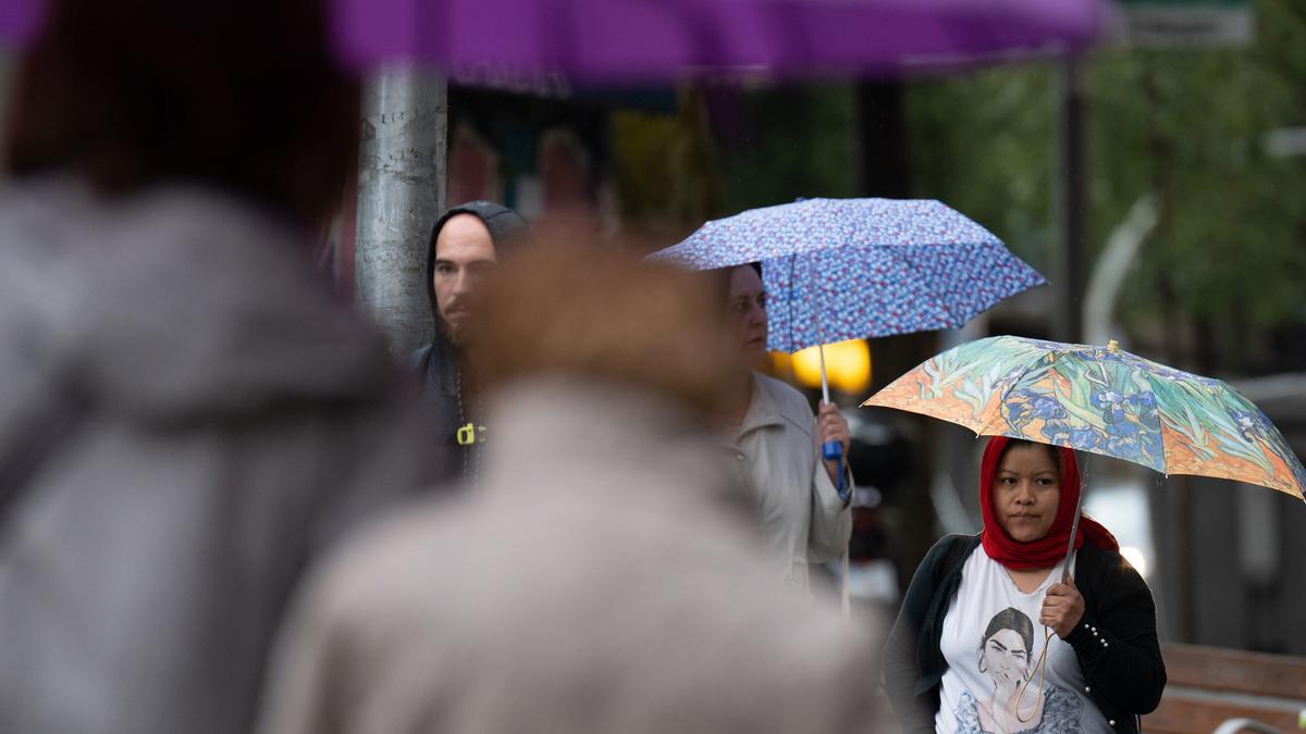 Varias personas con paraguas pasean por las calles.