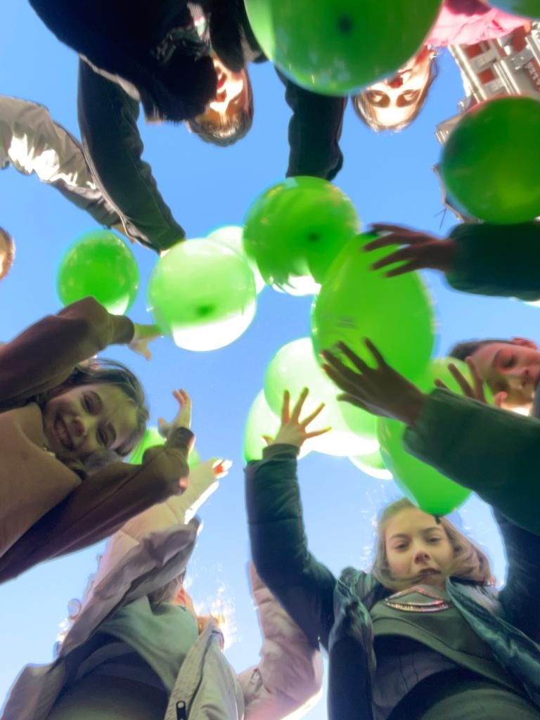 Niños del colegio Aniceto Sela lanzan globos verdes al aire.