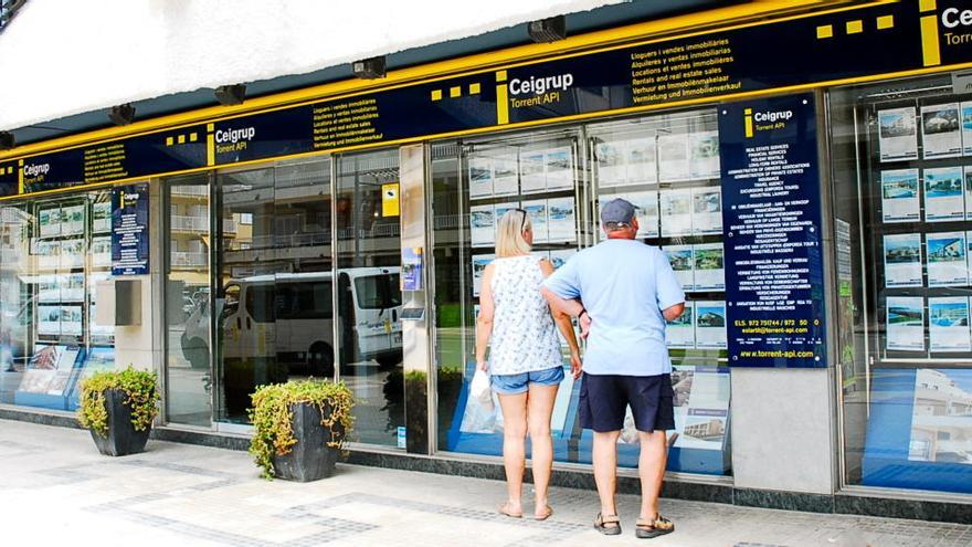 Una parella mira ofertes d&#039;immobles penjades en una oficina de la immobiliària gironina Ceigrup