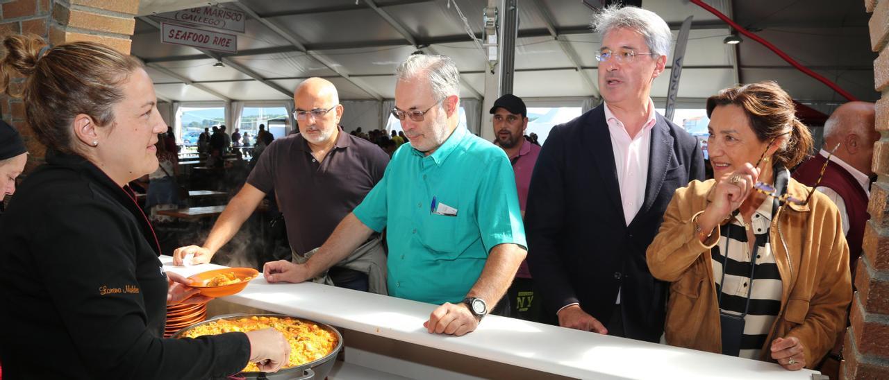 La subdelegada del Gobierno y el alcalde durante el recorrido por la fiesta, en el puesto de arroz de mariscos gestionado por la cocinera local Lorena Moldes, del restaurante Pan de Millo. |   //  FDV