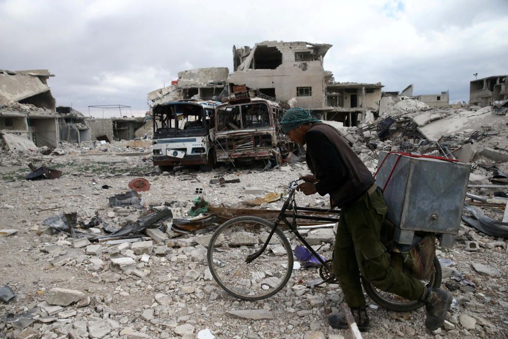 A man walks with his bicycle at a damaged site ...