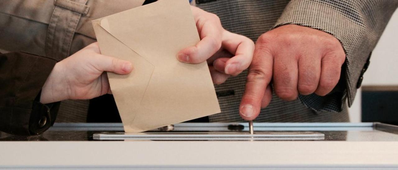 Electores depositan el sobre con el voto en una urna.