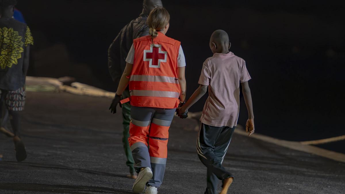 Una voluntaria de Cruz Roja con un menor tras su llegada a El Hierro en cayuco.