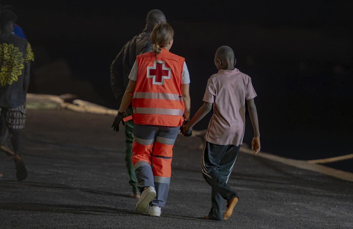 Una voluntaria de Cruz Roja con un menor tras su llegada a El Hierro en cayuco.