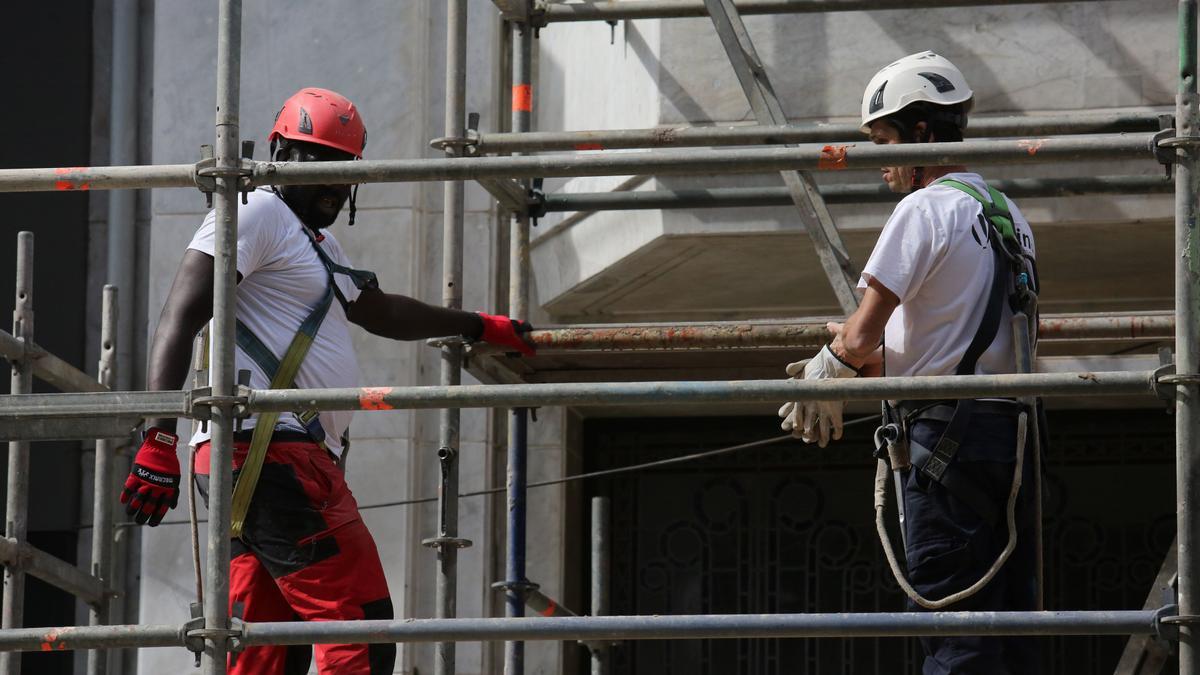 Obreros trabajando en un andamio en verano.