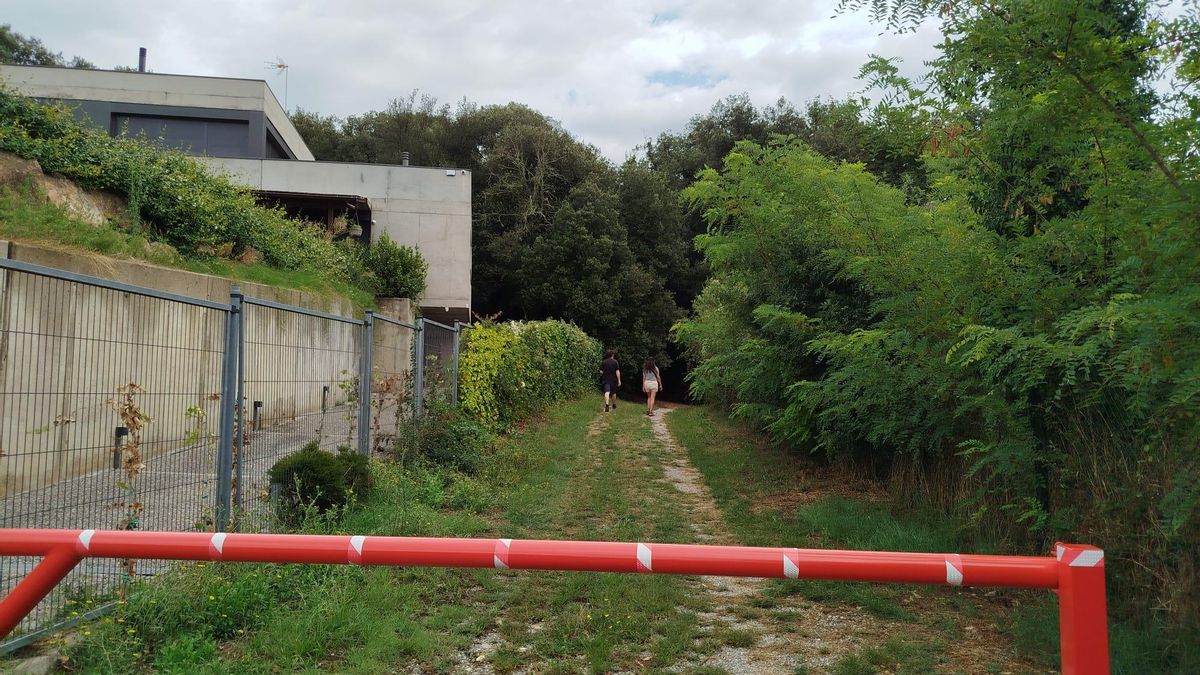Un dels camins per on van a passejar els veïns, amb una casa al costat dels arbres.