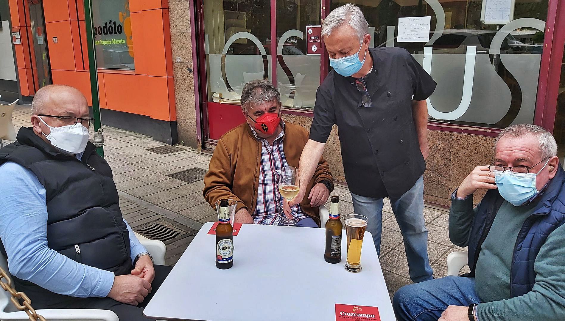 Gaspar Rodríguez sirve unas consumiciones a Chus Rosete, Manolo Rosete y Secundino Miranda, en la terraza de su restaurante de Sama. | E. P.