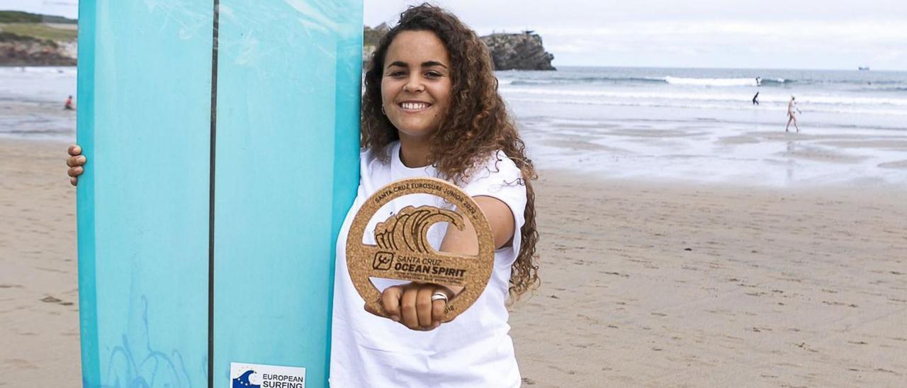 Daniela Sevillano, en Salinas, con su tabla de longboard y el trofeo de campeona del mundo junior.