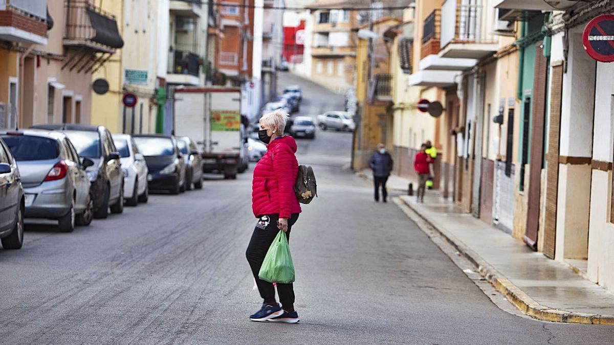 Una vecina de Anna cargada con bolsas cruza una calle de la localidad, en una imagen de archivo | PERALES IBORRA