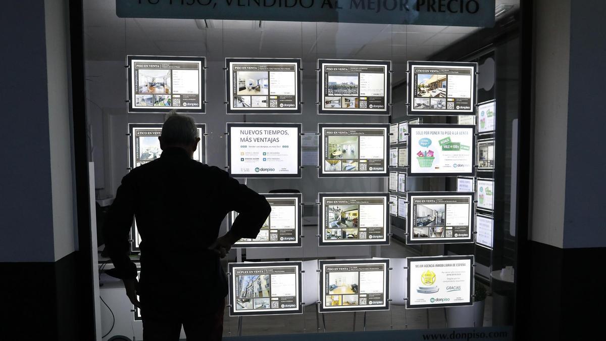 Un hombre mira los carteles de pisos en una inmobiliaria de València.