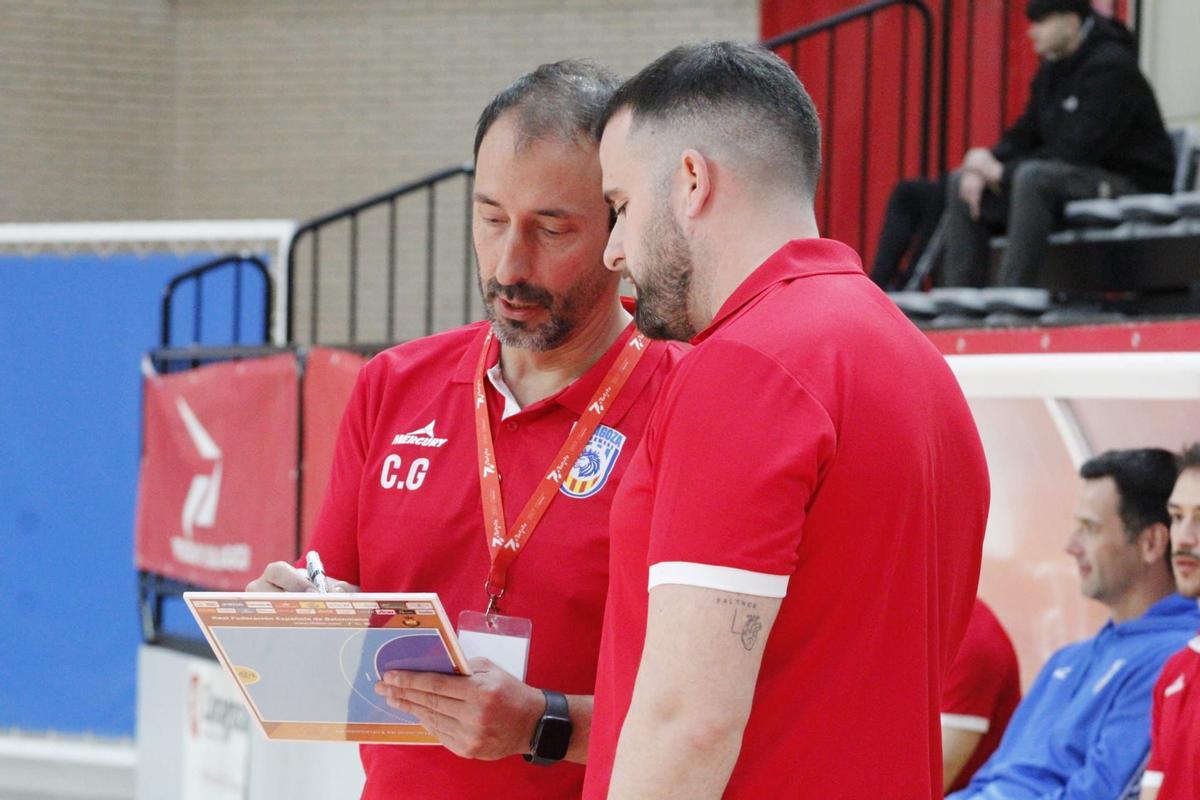 Carlos García habla con un miembro de su cuerpo técnico durante un partido.