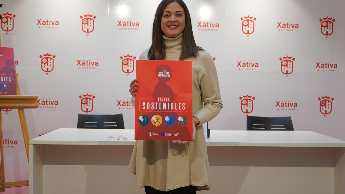 La concejal María Beltràn posa con el cartel de las iniciativas de Fallas sostenibles en Xàtiva.
