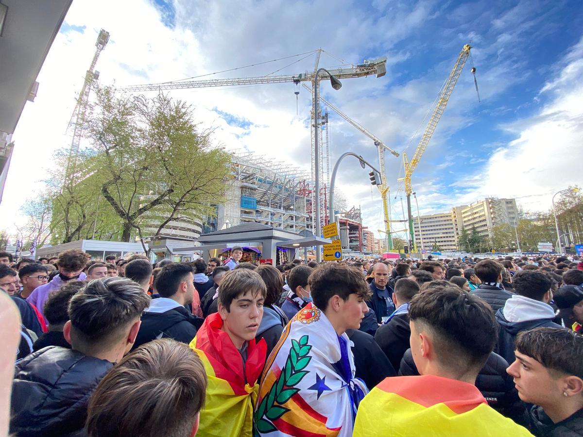 Jóvenes seguidores blancos con bandera de España y del Real Madrid sobre sus hombros.