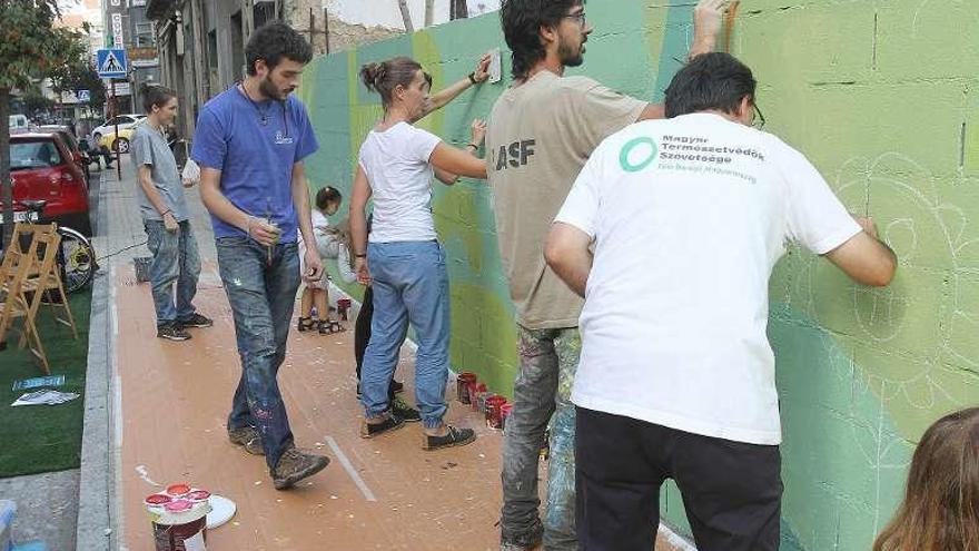 Activistas y voluntarios pintan el muro. // Iñaki Osorio