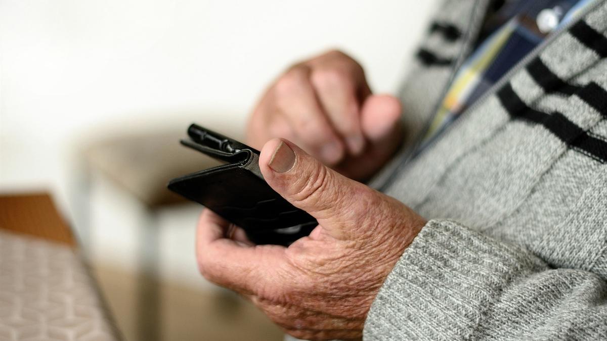 Una persona mayor con un teléfono en la mano