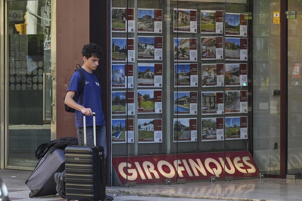 Una persona davant l’aparador d’una immobiliària a Girona.