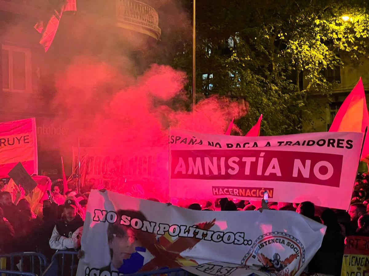 Pancartes contràries a l'amnistia envoltades de fum a prop de la seu del PSOE al carrer Ferraz de Madrid