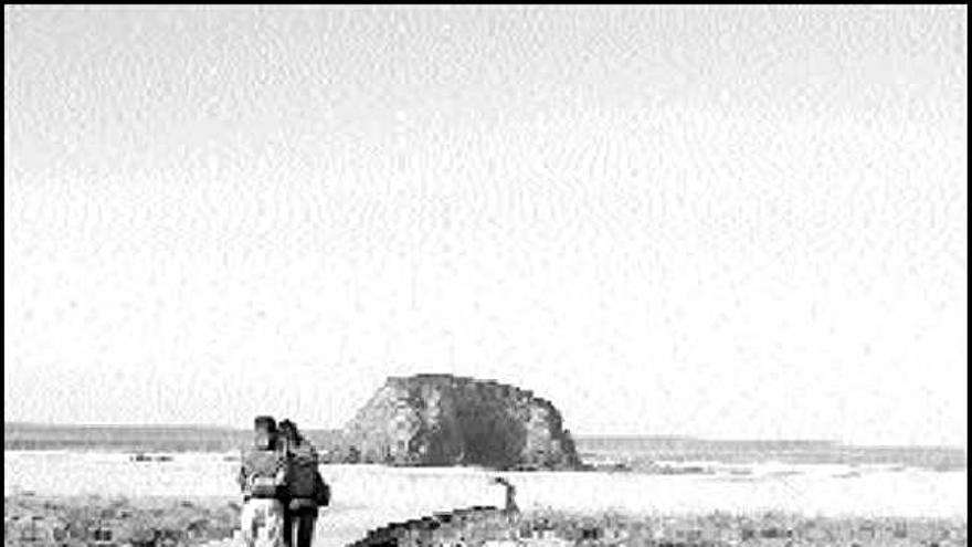 Una pareja paseando, ayer, en una playa de la comarca.