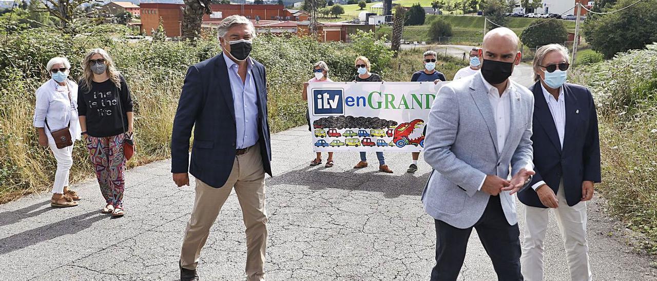 De izquierda a derecha, Margarita Simón, Pilar Granjo, Eladio de la Concha García-Mauriño, Jesús Martínez Salvador y Alberto López-Asenjo. Detrás, vecinos de Granda con una pancarta de rechazo hacia la ITV. | Marcos León