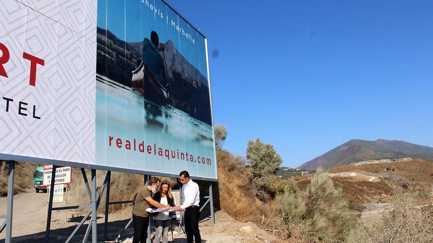 Los concejales de Izquierda Unida junto al cartel que anuncia la nueva urbanización.