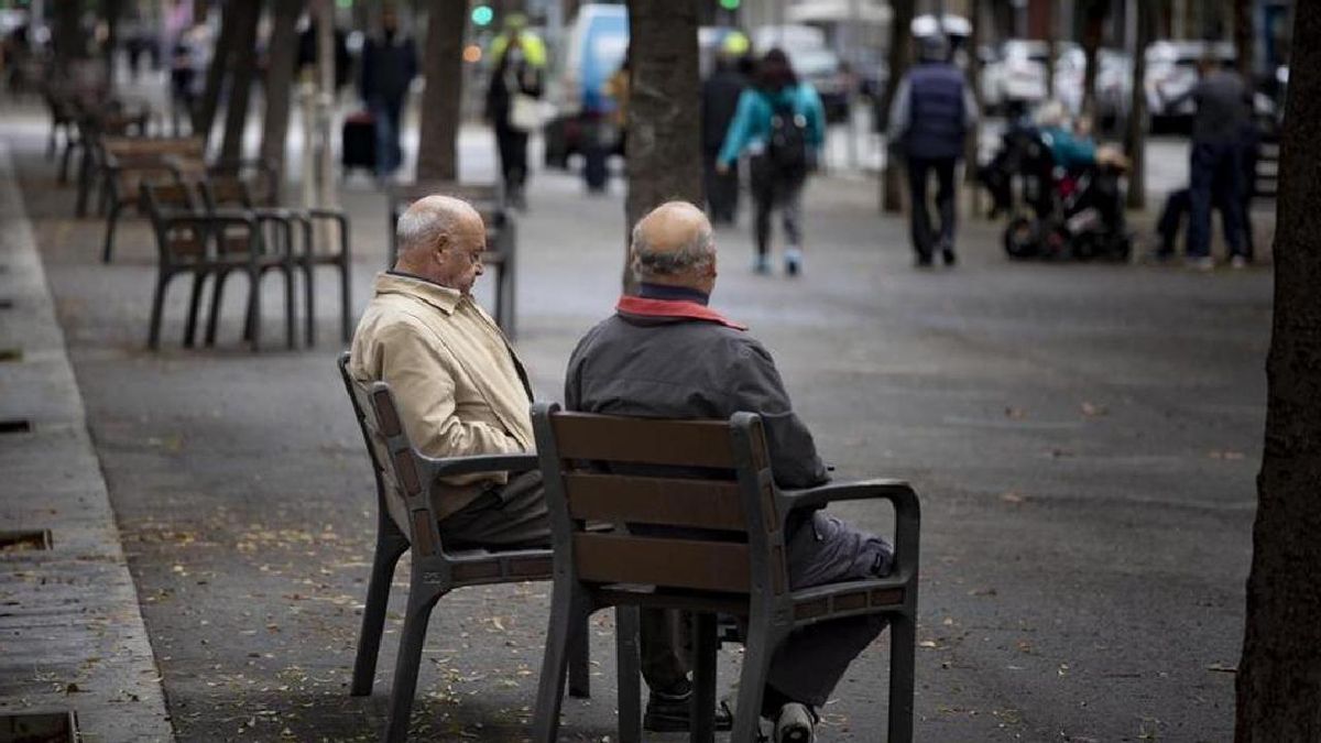 Dos pensionistas conversan mientras descansan en un banco.