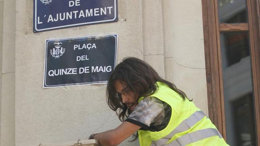 Un miembro de movimiento 15M coloca una placa con el nombre Plaza del 15 de mayo&#039; para sustituir la de la Plaza del Ayuntamiento de Valencia, durante las protestas de 2011.