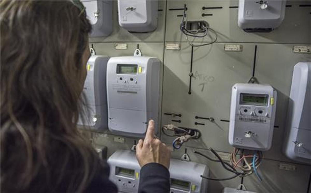 Una mujer mira un contador de luz.