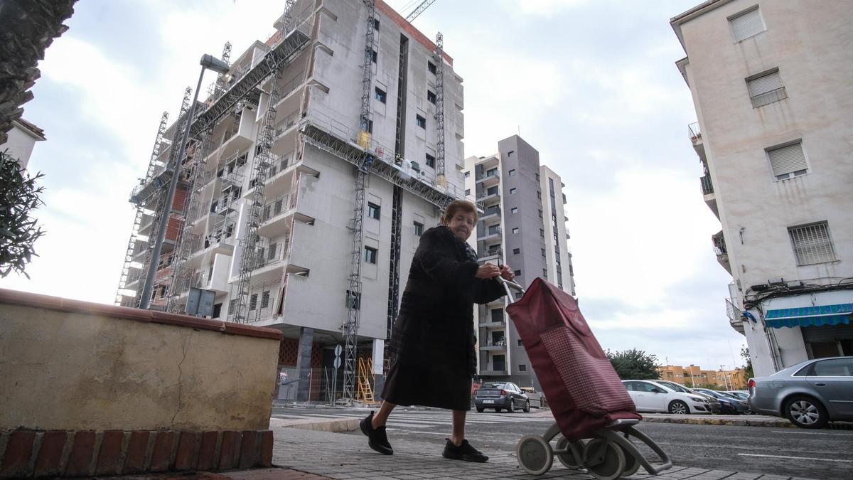 Una vecina se pasea entre un edificio en plena construcción y una promoción antigua de viviendas en San Antón.