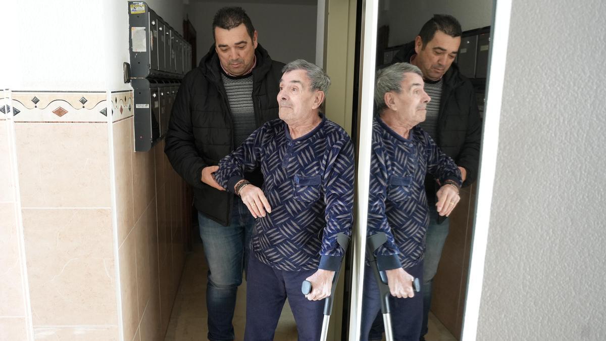 Juan Criado sale del ascensor, ayudado por Manuel García, presidente de la AVV San José Obrero.