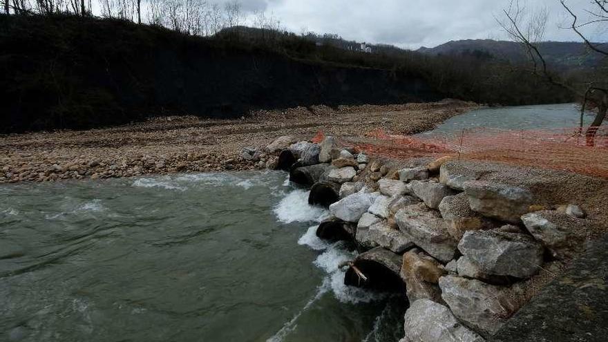 El cauce del río Nalón, completamente desviado en Blimea, con la escollera de piedras y, al fondo, la escombrera sobre la que pasa el Corredor.