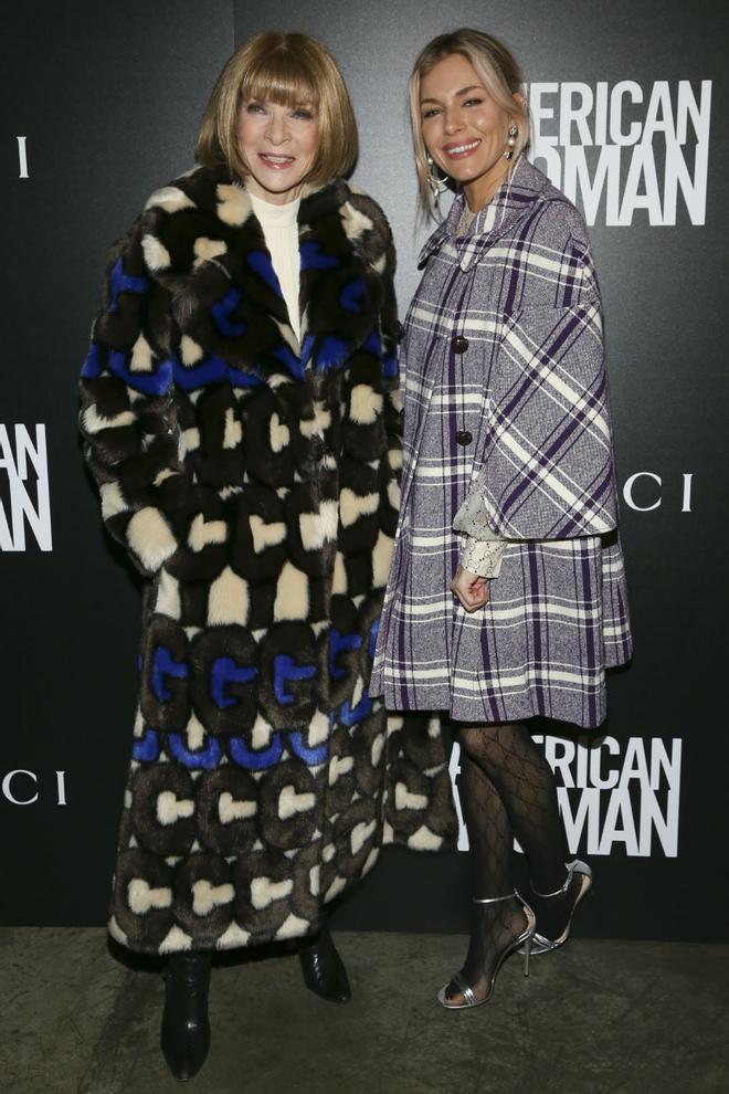 Sienna Miller posa junto a Anna Wintour con un original abrigo maxi de cuadros con el que remató un look protagonizado por unas medias de rejilla en color negro