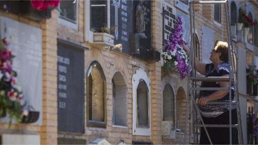 Una mujer cambia las flores de un nicho del Cementerio General de Valencia, ayer.