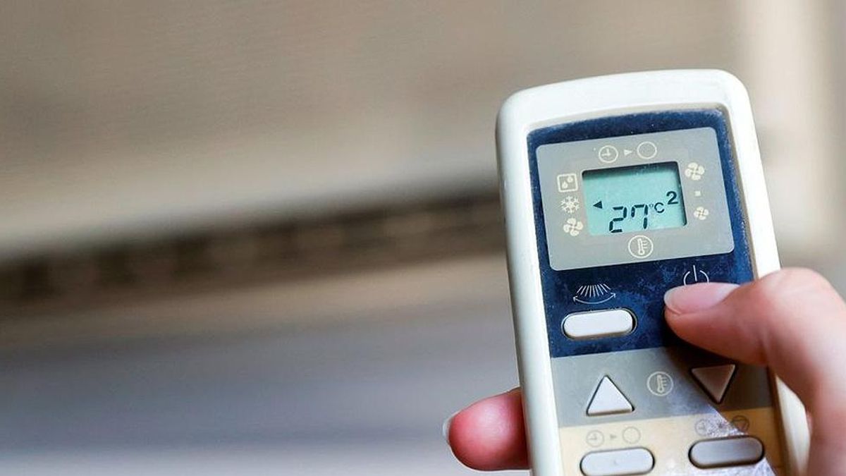 Una persona enciende el aparato de aire acondicionado.