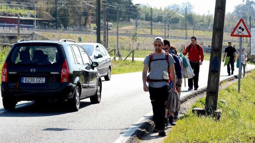 Peregrinos transitando ayer cerca de los coches en Alba. // Rafa Vázquez