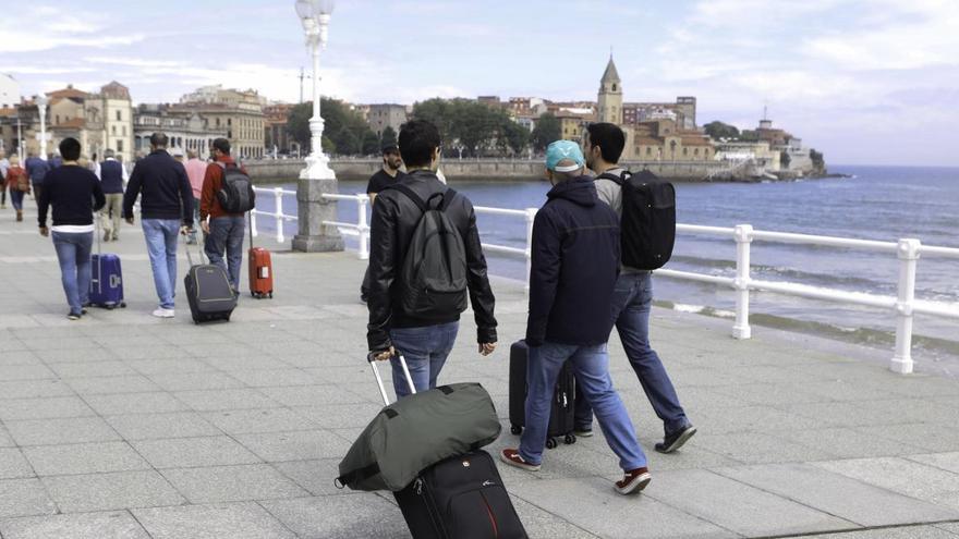 Unos viajeros arrastrando sus maletas por Gijón.