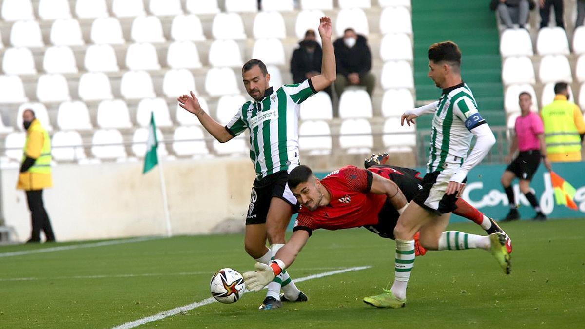 Miguel Guerrero disputa un balón a De las Cuevas y Javi Flores en El Arcángel.