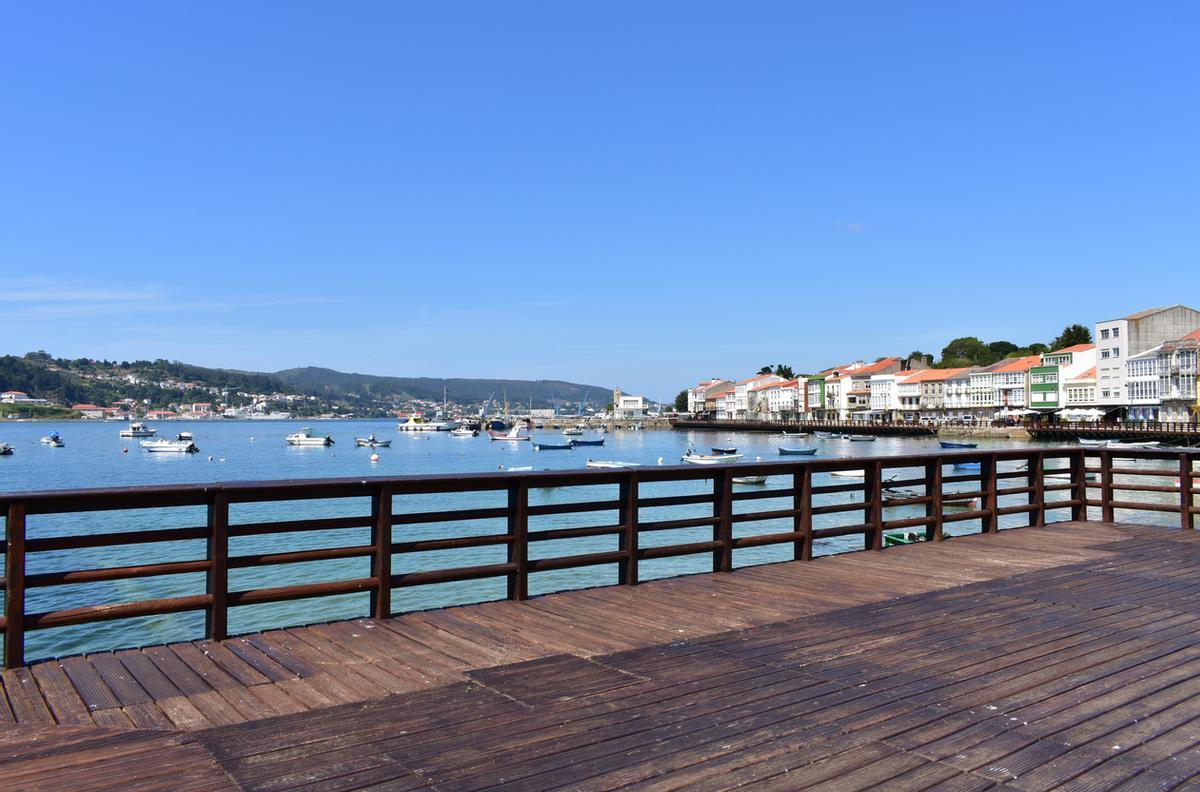 Pequeño pueblo de pescadores con paseo marítimo de madera y pasamanos. Mugardos, España
