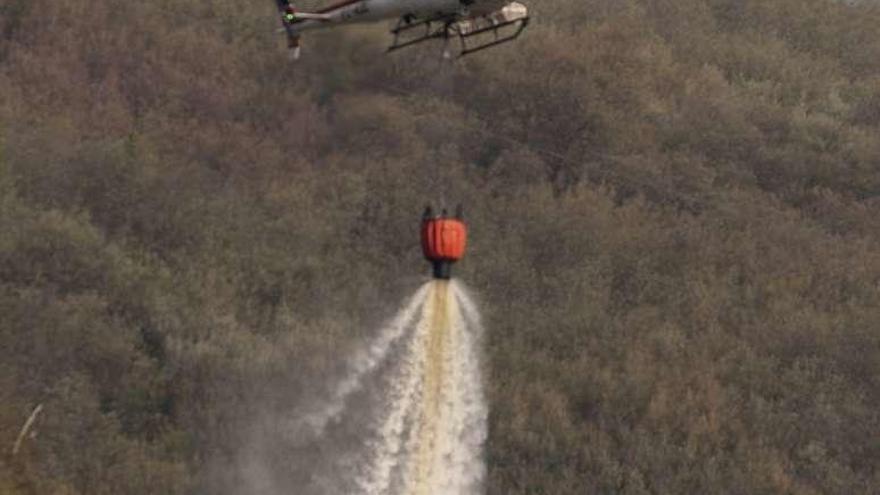 Un helicóptero descarga agua en la extinción de un incendio.