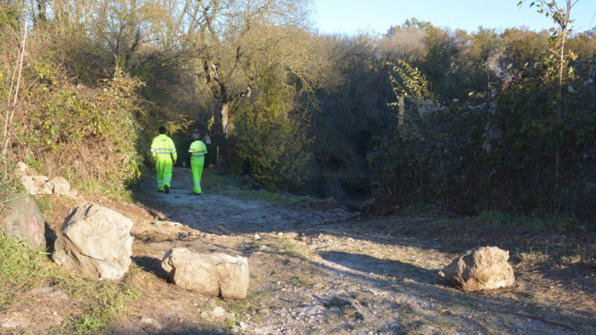 Dos operaris treballant en la restauració del camí del Bac de la Pradella, a Olot.