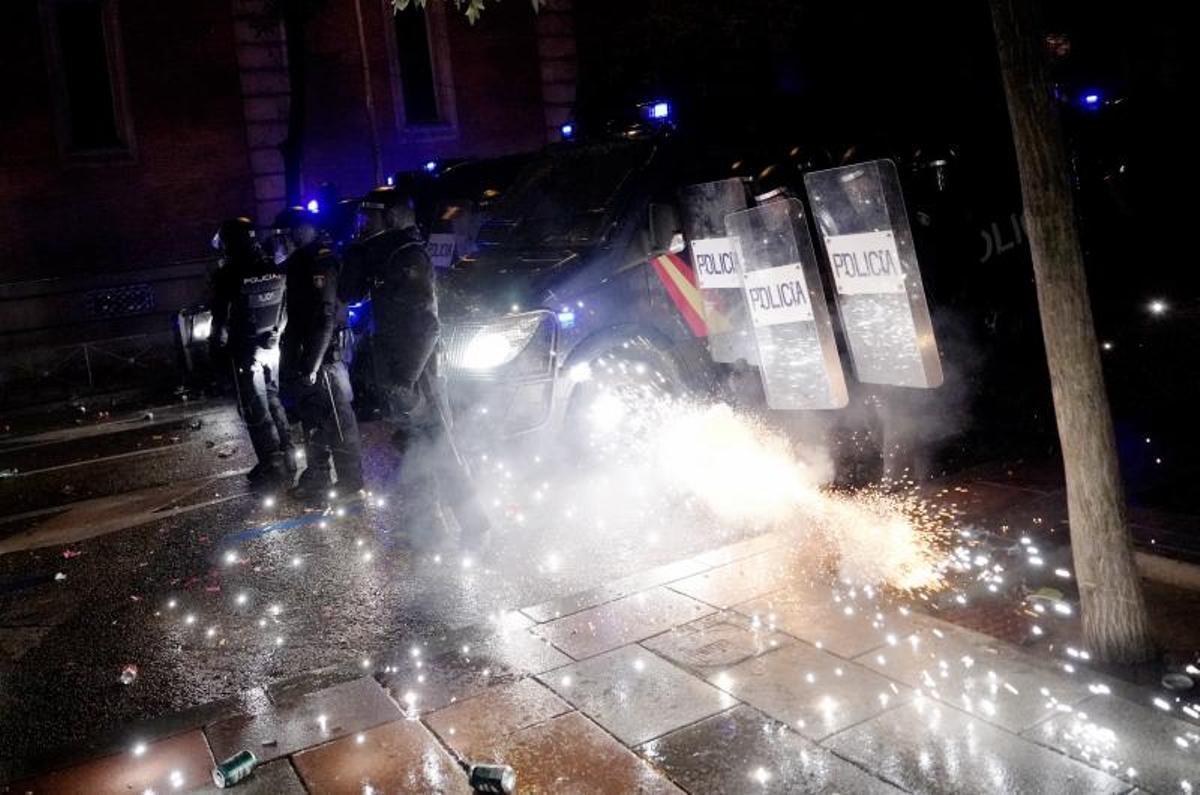 Los manifestantes de la calle Ferraz lanzan petardos y bengalas a los policías antidisturbios.