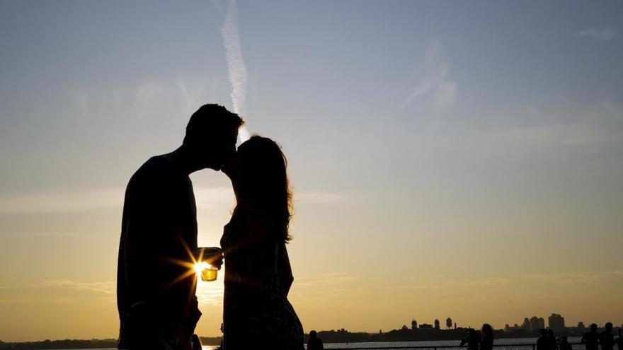 Una pareja se besa durante el atardecer.