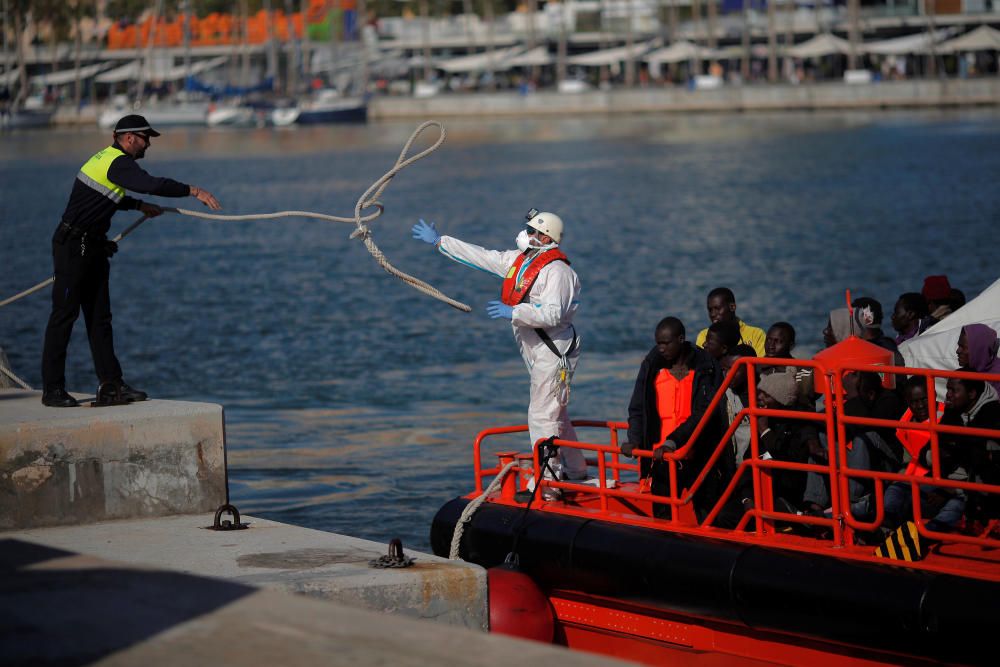 Migrants stand on a rescue boat upon arriving at ...