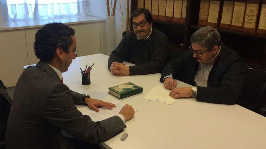 El alcalde de Miño, al fondo a la izq., junto a su socio en la firma del pacto de gobierno.