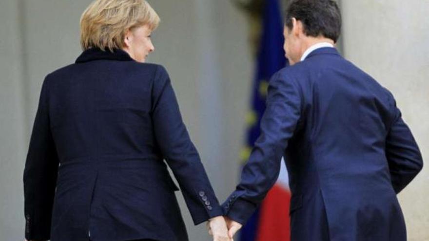 Nicolas Sarkozy coge la mano de Angela Merkel para entrar en el Elíseo. / reuters